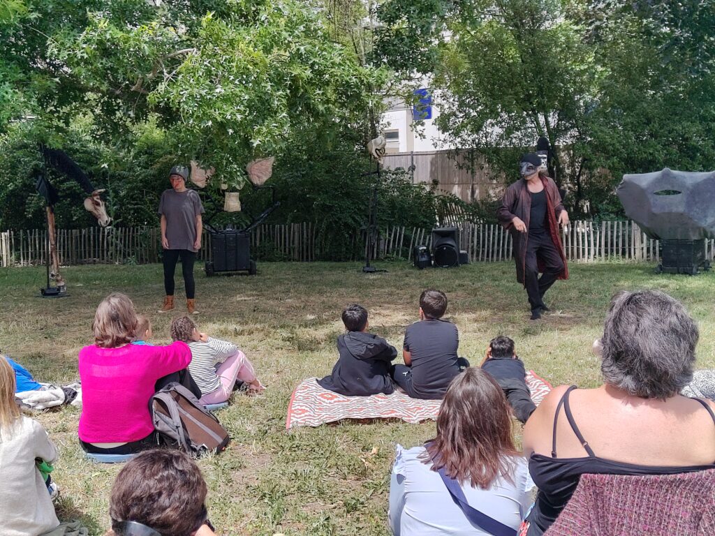 Spectacle théâtral en plein air, avec le public assis de dos